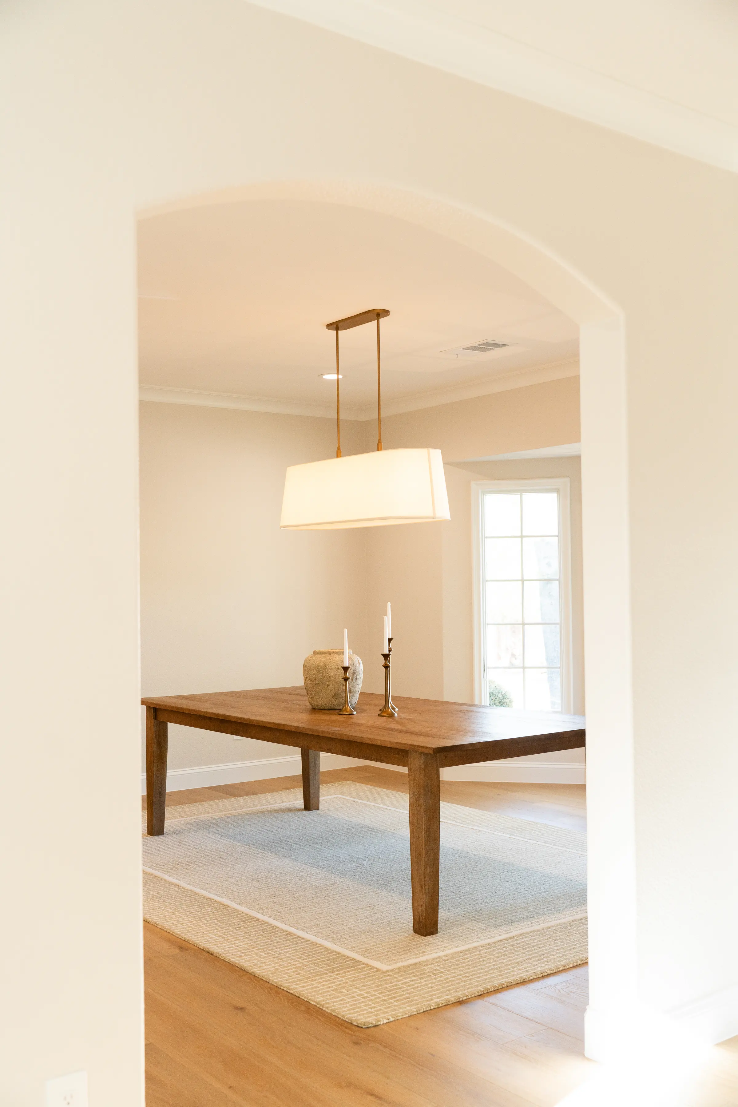 Dining room seen through an arched opening, with a pendant over a wood table